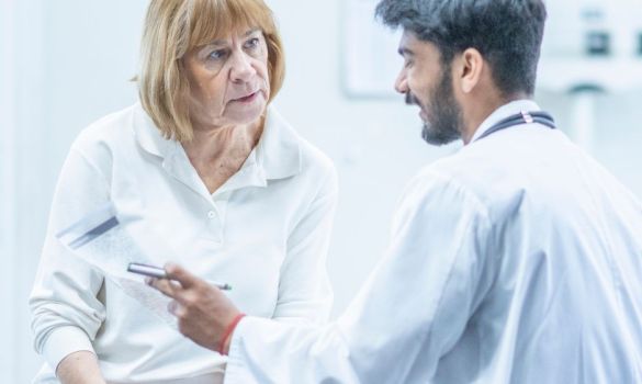 A doctor explains hearing benefits to an older female patient.